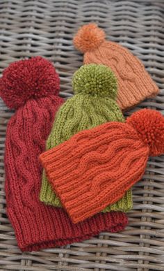 three knitted hats sitting on top of a wicker basket