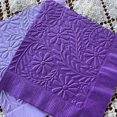 three purple napkins are sitting on a doily