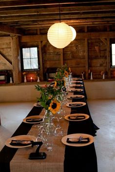 a long table with place settings and sunflowers in vases on the tables