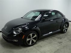 a black volkswagen beetle parked in a garage