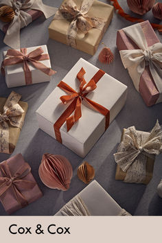 many wrapped presents with ribbons and bows on the floor next to each other, all in different colors