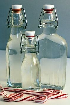 three glass bottles with candy canes in front of them