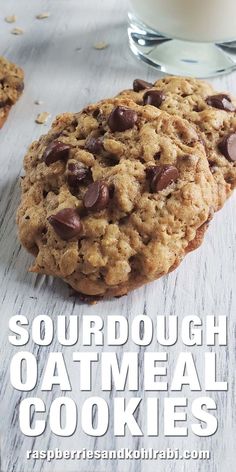 a close up of two cookies on a table with milk in the background and text reading sourdough oatmeal cookies