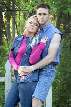 a man and woman are hugging in front of some trees with their arms around each other