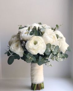 a bridal bouquet with white flowers and greenery