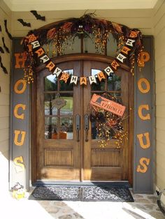 a front door decorated for halloween with pumpkins, bats and decorations hanging from it