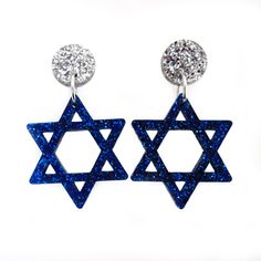 Enjoy an extra bright Festival of Lights with these Glittery Star of David Earrings! * Each pendant is laser cut from glitter acrylic which makes each earrings extremely lightweight. They won't weigh down your ears or your style! * Be bold wearing these decently sized Blue and Silver Star of David Earrings! Each earring hangs down a total of 1.75″ from top to bottom. * Star of David hangs off a .5″ circle with holds your choice of earring post option! You can choose which earring post or clip on Witch Earrings, Star Of David Pendant, Glitter Acrylic, Festival Of Lights, Cute Gift Boxes, Glitter Earrings, Glitter Acrylics, Earring Post, Handcrafted Artisan Jewelry