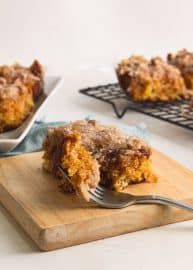 a wooden cutting board topped with pieces of cake next to a fork and cooling rack