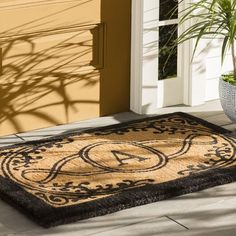 a door mat on the ground with a potted plant next to it in front of a house