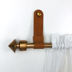 the curtain rod is attached to the wall with two brass handles and a leather handle