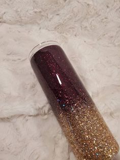 a purple and gold glitter tumbler sitting on top of a white fur covered floor