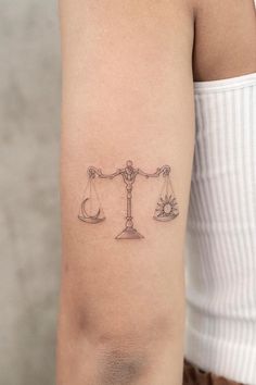 a woman's arm with a tattoo on it that has two scales in the middle