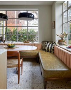 a kitchen with a table, bench and windows