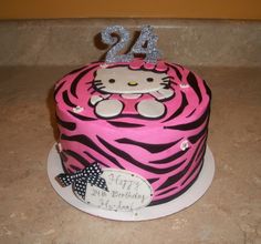 a hello kitty birthday cake with pink and black zebra print on the top, decorated with silver glitter numbers