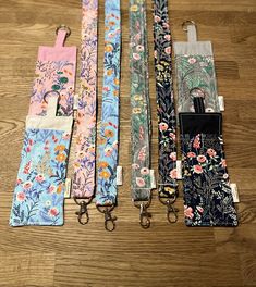 four lanyards with floral designs on them sitting on a wooden floor next to each other