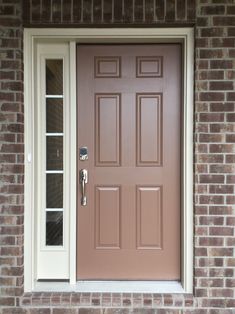 a brown door with two sidelights on a brick building