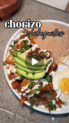 a white plate topped with food next to beans and avocado