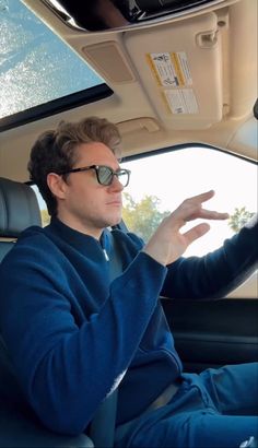 a man sitting in the driver's seat of a car with his hands out