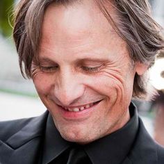 a close up of a person wearing a suit and tie with his eyes closed smiling