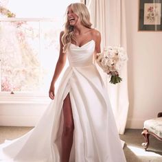 a woman in a white dress is smiling and posing for the camera with her bouquet