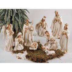 a group of nativity figurines sitting next to a christmas tree