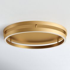 a gold circular light fixture on a white wall