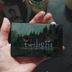 a person holding up a card with the words twilight on it in front of a forest