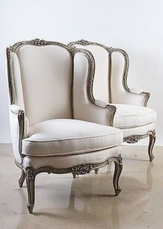 an antique style chair with white upholstered back and arm rests against a wall