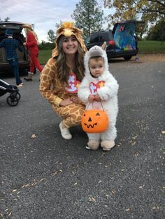 a woman in a giraffe costume holding a small child wearing a pumpkin hat