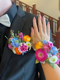 the bride and groom are wearing flower wrist corsages