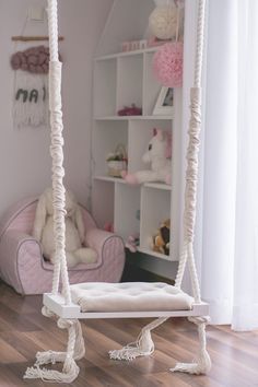 a white swing bed in a child's room with pink furniture and accessories on the walls