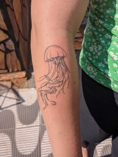 a person with a tattoo on their arm that has a jellyfish in the water