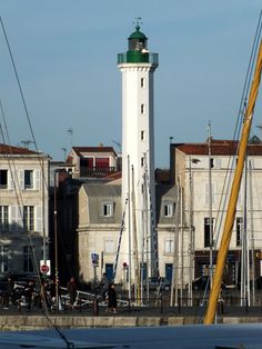 a tall white tower with a green top next to other buildings and boats in the water