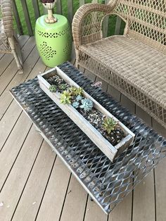 a table with two trays filled with succulents on top of it