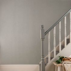 a white stair case next to a banister in a room with grey wallpaper