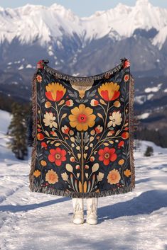 a woman standing in the snow holding up a blanket