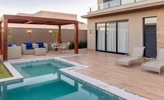 an outdoor pool with lounge chairs next to it and a covered patio in the background