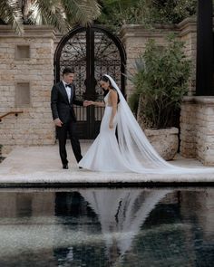 a bride and groom standing in front of a pool