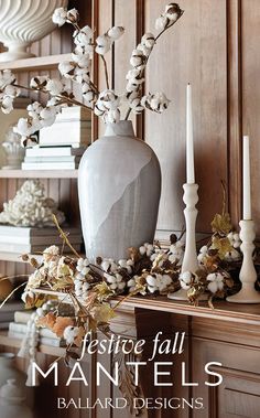 a vase with flowers and candles on a mantle