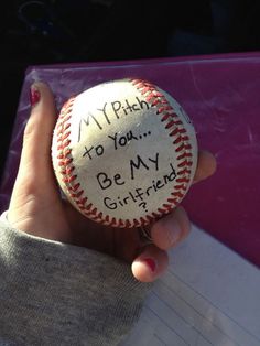 a person holding a baseball that says, my pitch to you be my girlfriend?