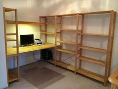 a computer desk sitting in the corner of a room next to a bookshelf