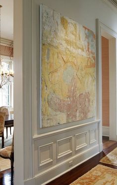 a large painting hanging on the wall in a living room next to a chandelier