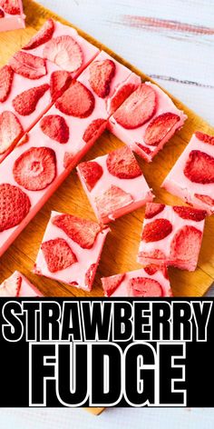 strawberry fudge on a cutting board with strawberries cut in half and sliced into squares