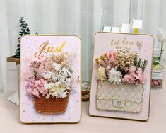 two cards with flowers in them sitting on a table