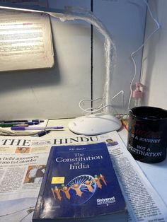 a book sitting on top of a table next to a cup and some paper with writing