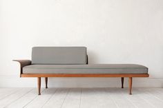 a gray couch sitting on top of a white floor next to a wooden table and chair