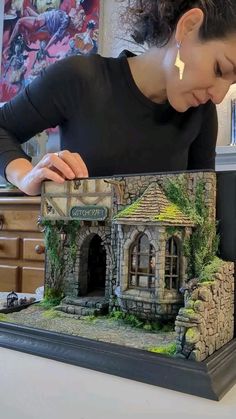 a woman is looking at a miniature house