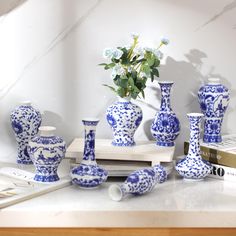 blue and white vases sitting on top of a table next to a flower pot