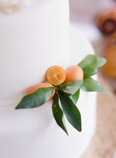 a white cake with oranges and leaves on top