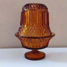 an orange glass vase sitting on top of a table